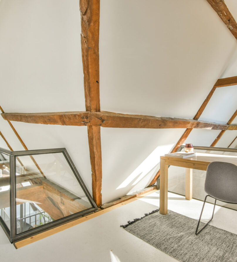 Interior of light home mansard office with desk and lamp near window