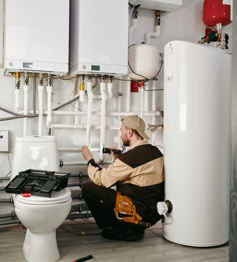 Young man in workwear using handtools during repairing work in toilet